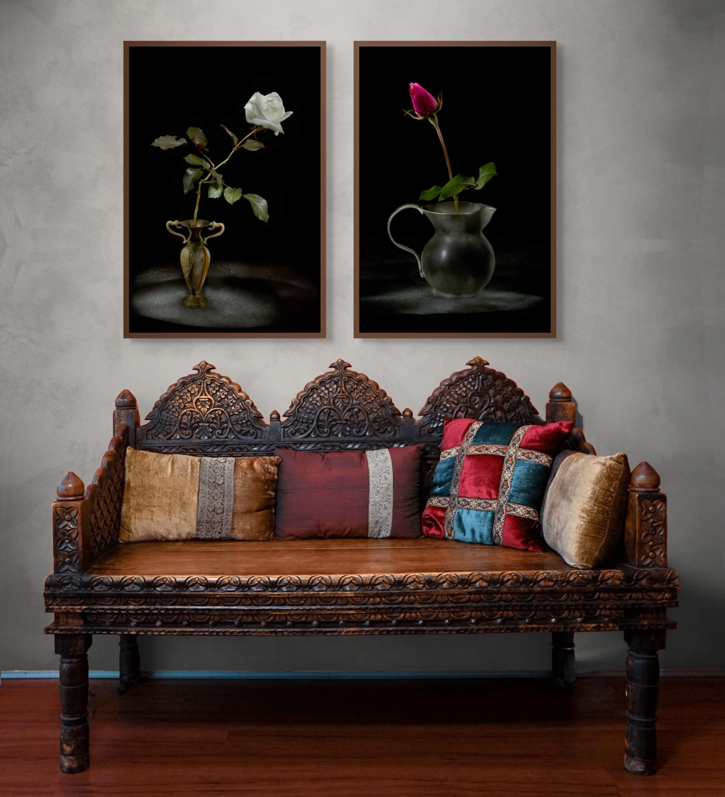 Mockup di interior design con un dittico fotografico di Antonio Milesi: "Elegia della Luce Bianca" e "L'Anima e il Tempo". Le due opere in formato verticale sono esposte sopra una panca antica in legno intagliato con cuscini colorati, su una parete grigio chiaro. Interior design mockup featuring a photographic diptych by Antonio Milesi: "Elegy of White Light" and "The Soul and Time". The two vertical works are displayed above an antique carved wooden bench with colorful cushions, against a light grey wall.