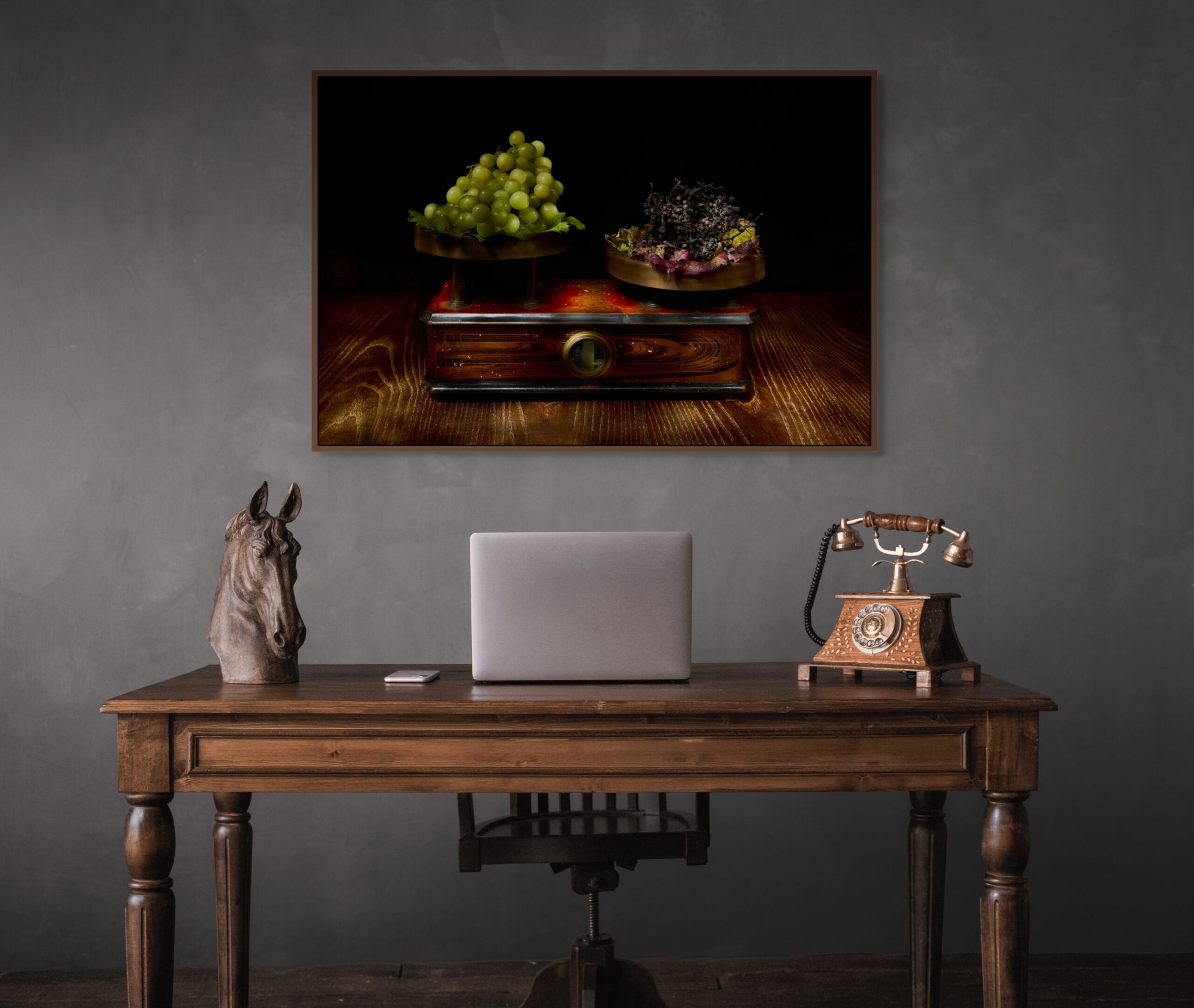 Mockup di uno studio professionale raffinato con scrivania in legno d'epoca. Sulla parete grigio antracite è appesa l'opera "La Bilancia del Tempo" di Antonio Milesi, che ritrae una bilancia antica con uva fresca e uva appassita in stile Vanitas. Refined professional study mockup with a vintage wooden desk. On the charcoal grey wall hangs "The Scales of Time" by Antonio Milesi, depicting an antique scale with fresh and withered grapes in Vanitas style.
